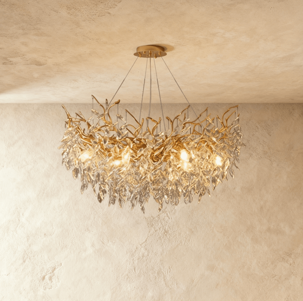 Clérachic gold branch chandelier glowing warm, cut crystal leaves cascading densely around its bulbs.