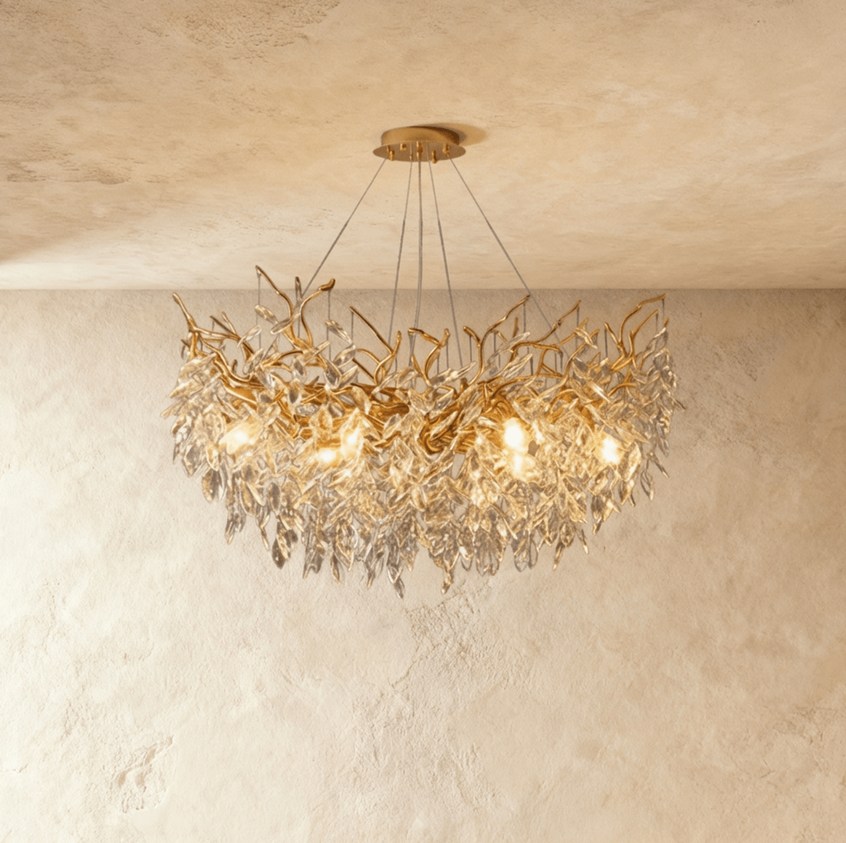 Clérachic gold branch chandelier glowing warm, cut crystal leaves cascading densely around its bulbs.