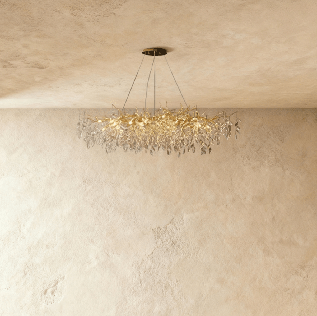 Clérachic crystal chandelier with a wide gold branch frame, its faceted leaves catching light near a plaster wall.