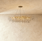 Clérachic elongated gold branch chandelier with crystal leaf clusters, its bulbs glowing beneath a round ceiling plate.