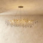 Clérachic oval gold branch chandelier glowing warm, cut crystal leaves trailing along its full width.