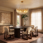 Clérachic crystal chandelier hung above an oval dining table, its gold branches glowing warm in a sunlit room.
