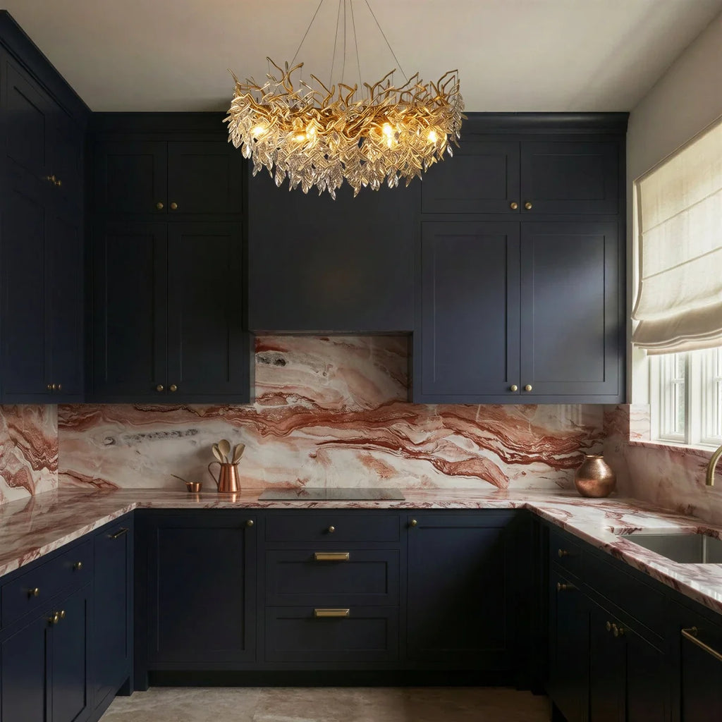 Clérachic crystal chandelier glowing above a kitchen island, its gold branches set against navy cabinetry and marble.
