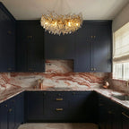 Clérachic crystal chandelier glowing above a kitchen island, its gold branches set against navy cabinetry and marble.