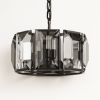 Clérachic round chandelier with smoky faceted crystal panes in a matte black frame, hung on a black chain against a pale wall.