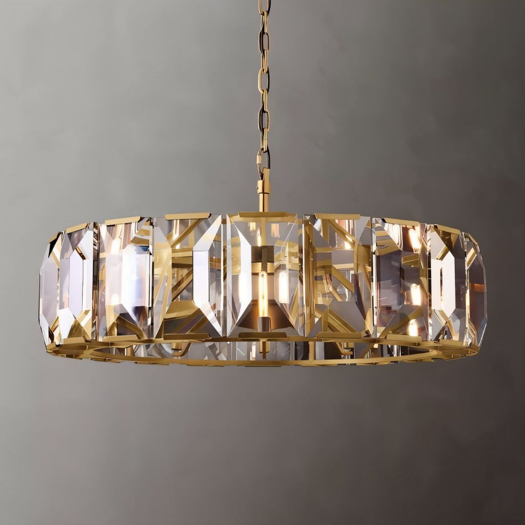 Clérachic wide ring chandelier with brass chain and frame, clear faceted crystal panes catching warm light on a grey backdrop.