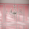 Clérachic six-light crystal chandelier in a silver finish with candle bulbs, hanging on a chain in a pink panelled room.