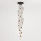 Wide spiral of Clérachic crystal pendants hung at many heights from a large round black ceiling plate, against a pale wall.