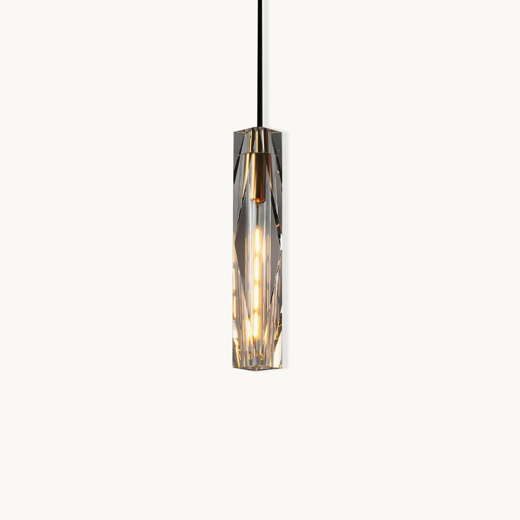 Slim Clérachic pendant with a faceted clear crystal shade, a brass-toned cap and a black cord, lit and shown on a plain white backdrop.