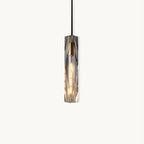 Slim Clérachic pendant with a faceted clear crystal shade, a brass-toned cap and a black cord, lit and shown on a plain white backdrop.