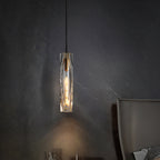 Faceted crystal Clérachic pendant glowing against a dark veined stone wall, casting a soft pool of light below it.