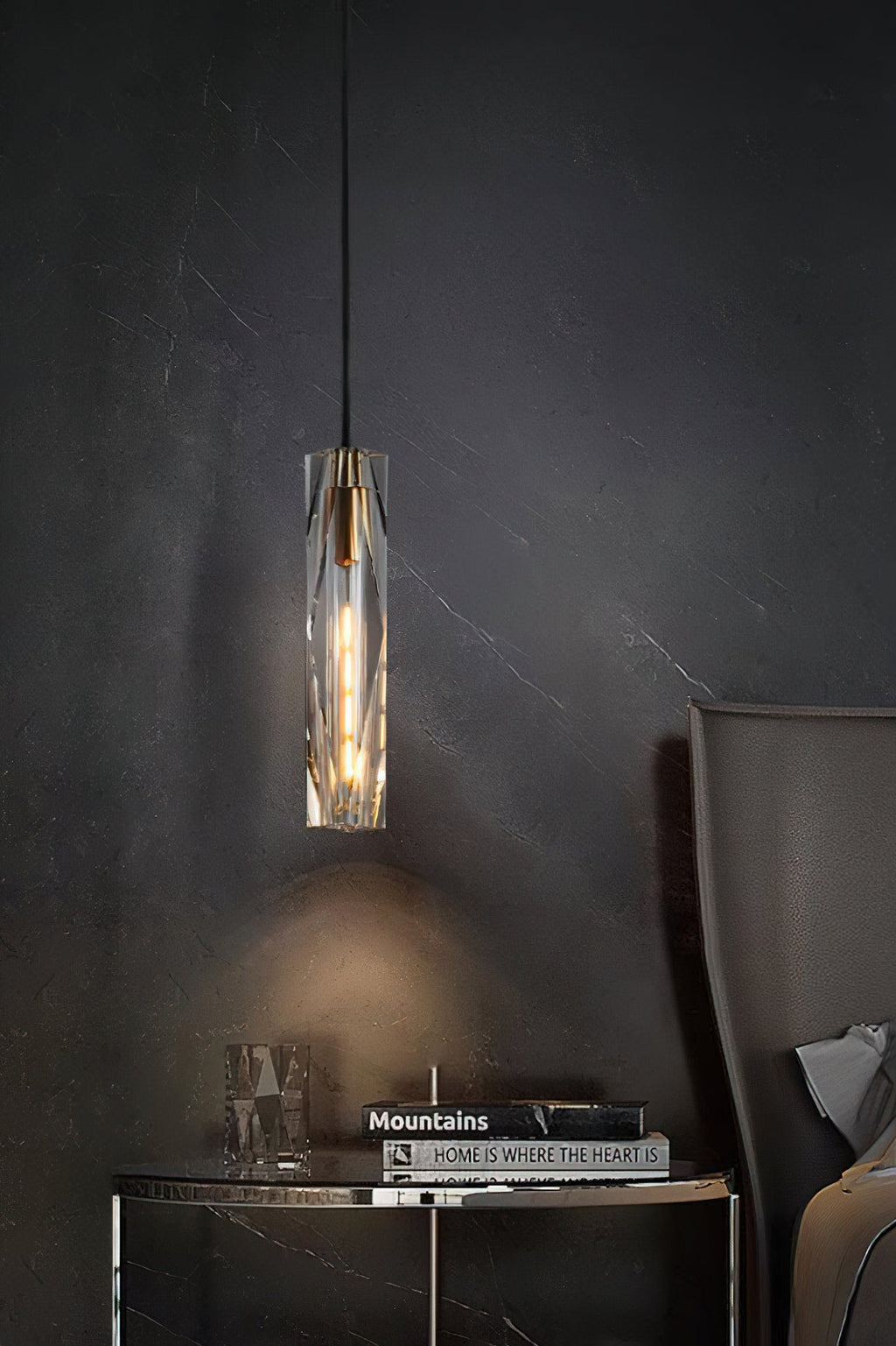 Clérachic crystal pendant above a dark round side table with a book stack and glass ornament, against a charcoal veined wall.