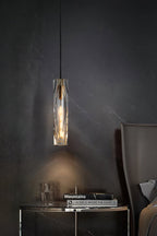 Clérachic crystal pendant above a dark round side table with a book stack and glass ornament, against a charcoal veined wall.