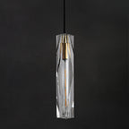 Close view of the faceted clear crystal shade on this Clérachic pendant, with its brass-toned cap and filament bulb on a dark ground.