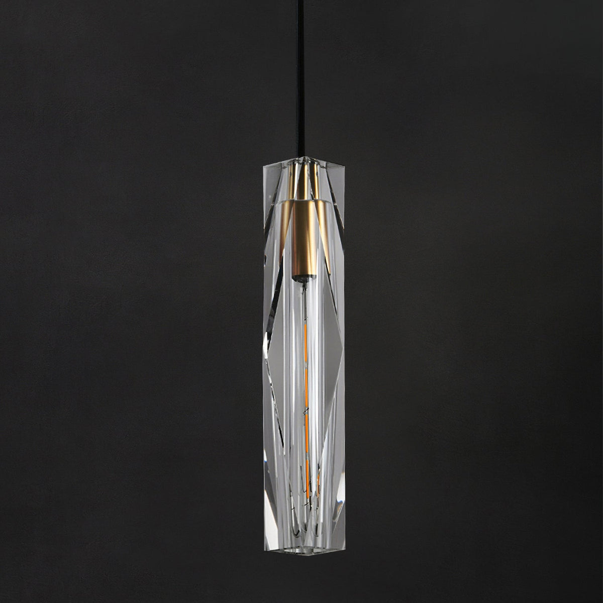 Close view of the faceted clear crystal shade on this Clérachic pendant, with its brass-toned cap and filament bulb on a dark ground.