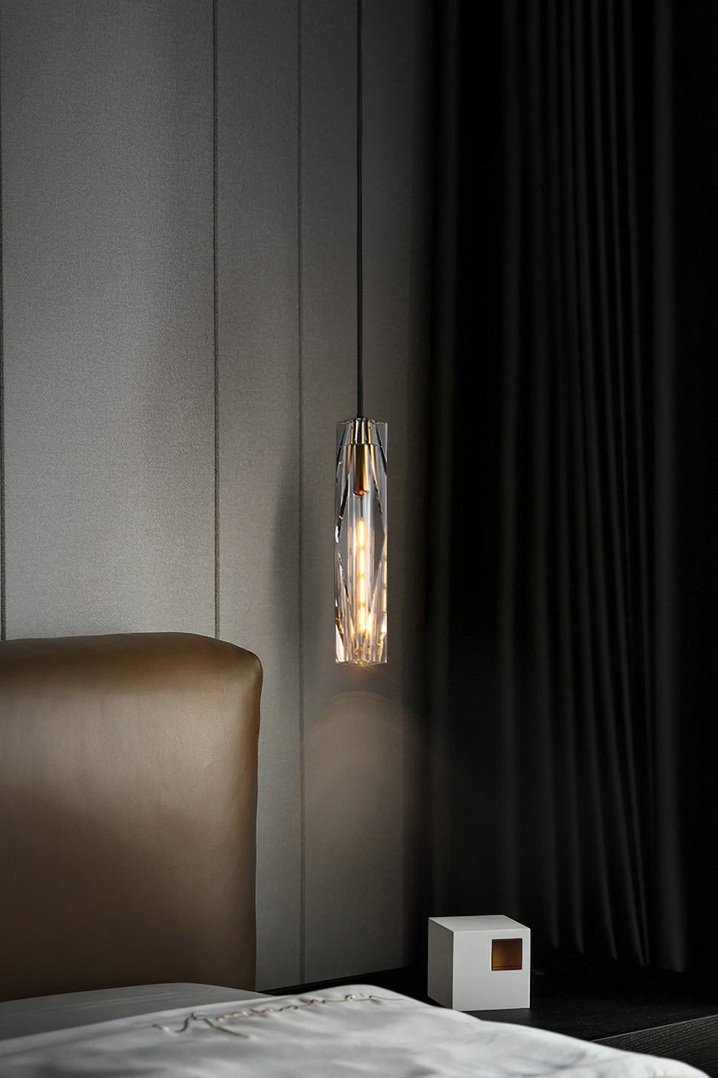 Small Clérachic crystal pendant in a dark bedroom, hanging in front of a pale panel with a heavy dark curtain beside it.