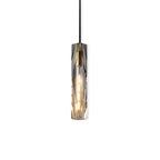 Clérachic pendant with a long faceted crystal shade, lit with a warm filament bulb, on a white background.