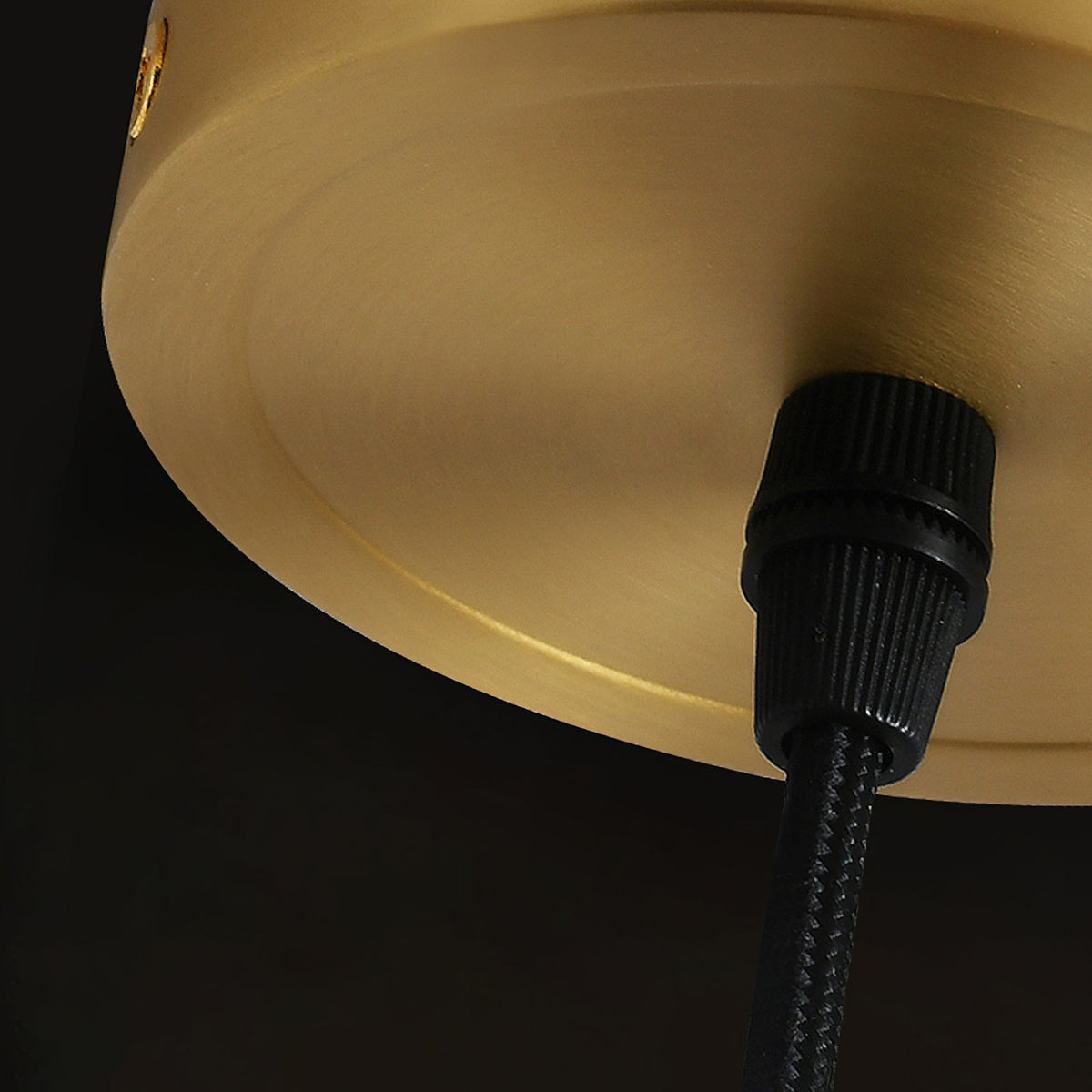 Close view of the brushed brass ceiling plate and black fabric cord on this Clérachic pendant.