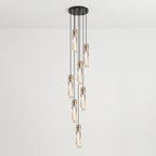 Seven Clérachic crystal pendants hung at different drops from one black ceiling plate, against a pale wall.