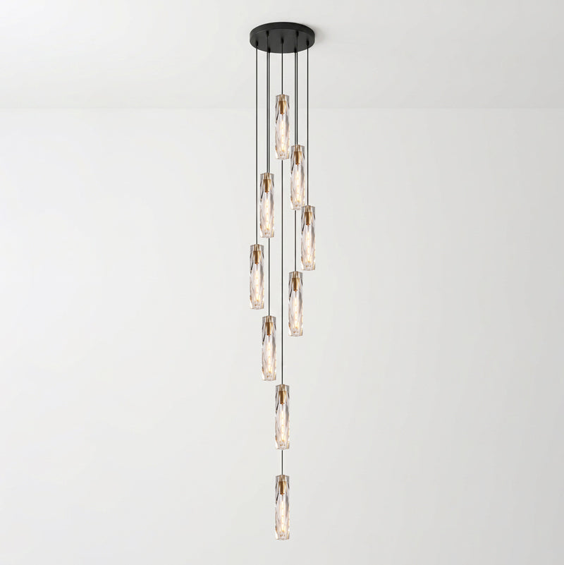 Tall cascade of Clérachic crystal pendants hanging at varied heights from a round black ceiling plate, against a pale wall.