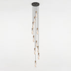 Long cluster of Clérachic crystal pendants dropping from a narrow round black ceiling plate in a spiral, against a pale wall.