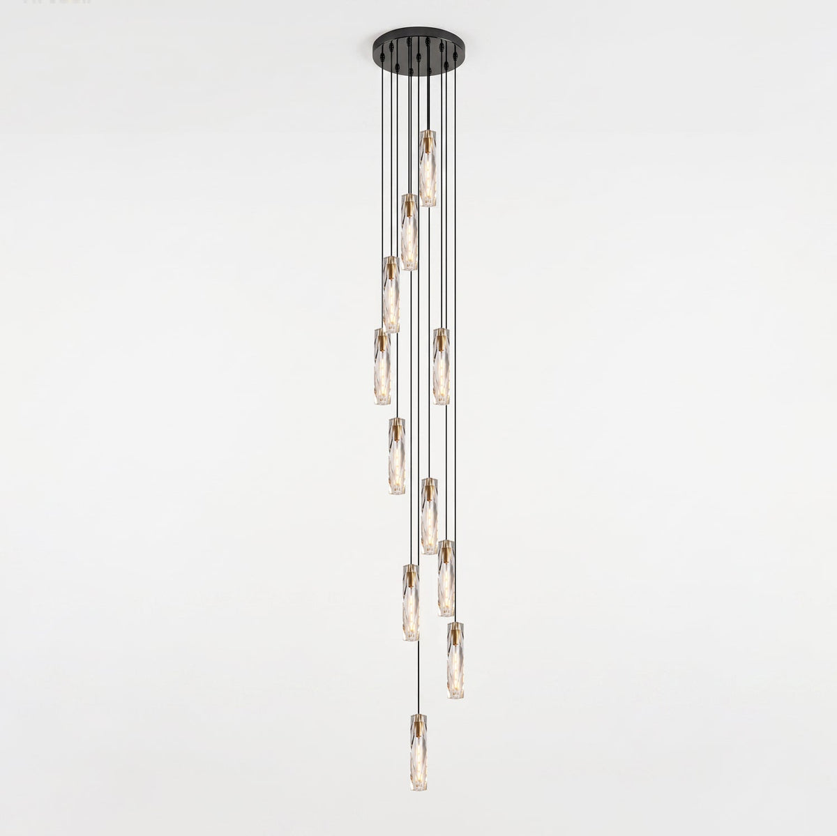 Long cluster of Clérachic crystal pendants dropping from a narrow round black ceiling plate in a spiral, against a pale wall.