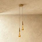 Clérachic crystal drop pendant light shown as a pair, two amber glass teardrops on brass stems against a plaster ceiling.