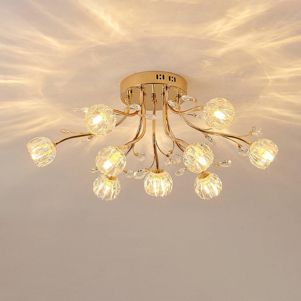 Lit gold ceiling light from Clérachic with clear ribbed glass flower shades, throwing patterned light across a cream ceiling.