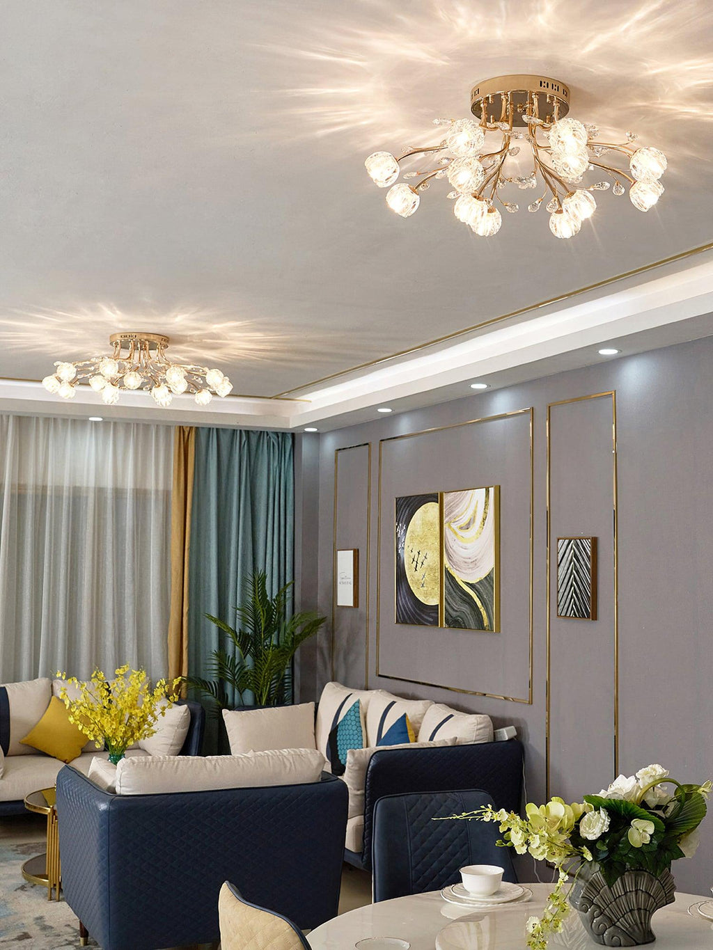 Gold Clérachic ceiling light with glass flower shades seen across a room with navy sofas, a dining table and teal curtains.