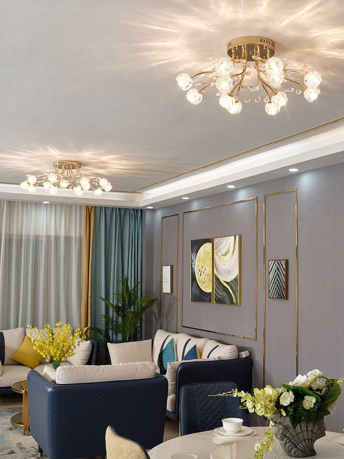 Gold Clérachic ceiling light with glass flower shades seen across a room with navy sofas, a dining table and teal curtains.