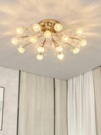 Gold branching ceiling light from Clérachic with many clear flower shades, glowing in a corner with pale curtains.