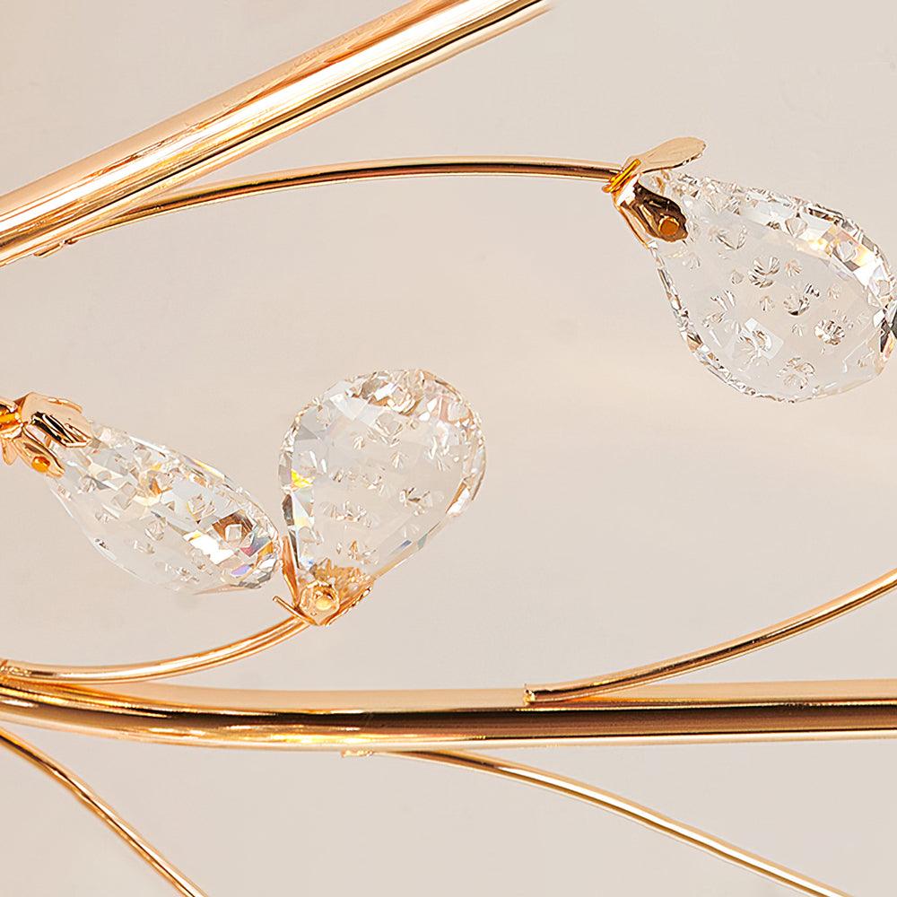 Close view of clear crystal leaf drops flecked with tiny bubbles on the slender gold stems of this Clérachic ceiling light.