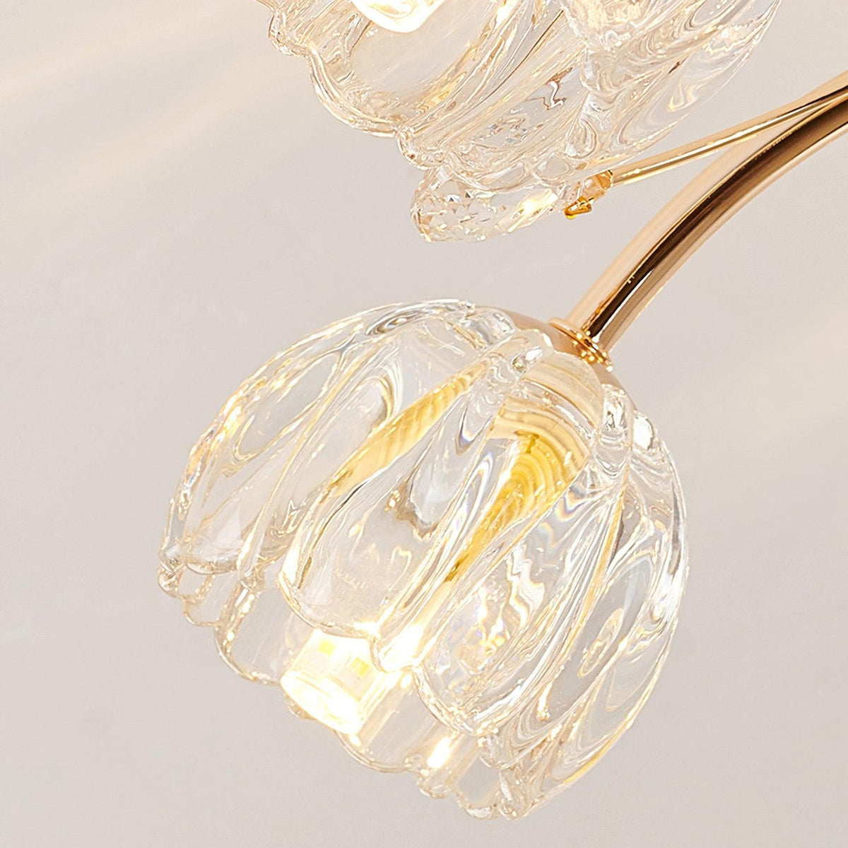 Close view of a ribbed clear glass flower shade on this Clérachic ceiling light, with a warm bulb glowing inside.