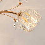 Close view of a clear glass flower shade on a gold stem of this Clérachic ceiling light, with a crystal leaf beside it.