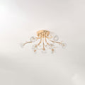 Smaller gold ceiling light from Clérachic with clear glass flower shades, unlit, mounted on a pale grey ceiling.
