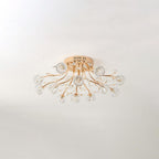 Gold ceiling light from Clérachic with clear glass flower shades and fine branches, unlit, above a softly shadowed wall.