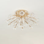 Unlit gold ceiling light from Clérachic with clear glass flower shades and crystal leaf details, on a bright ceiling.