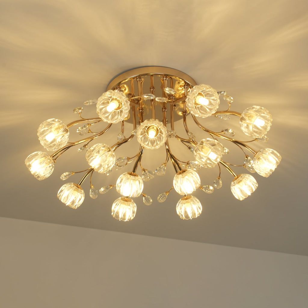 Lit gold ceiling light from Clérachic seen from below, with glass flower shades glowing warm against a patterned ceiling.