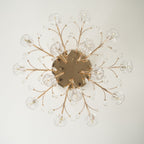 Unlit view from below of a gold Clérachic ceiling light, with branching stems and glass flowers around a round canopy.