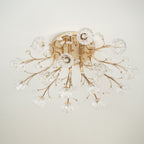 Gold flower-shade ceiling light from Clérachic, unlit, with crystal leaves and a few bulbs visible through the clear glass.