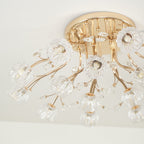 Close view of a gold canopy, curved stems and clear glass flower shades on this Clérachic ceiling light, unlit.