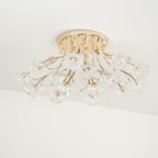 Side-on view of a gold flush ceiling light from Clérachic, with its stems fanning out and clear glass flowers below.