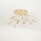 Unlit gold Clérachic ceiling light with a round canopy and a spread of clear glass flower shades, seen from the side.