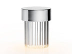 Close view of a Clérachic lamp with a chrome cap and deep vertical flutes in the glass, glowing softly at the base.