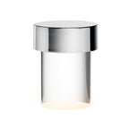 Close view of this Clérachic lamp on white, with a chrome cap over clear smooth glass and a warm glow at the base.