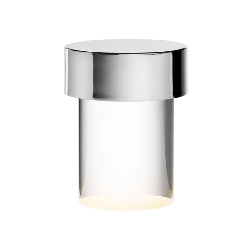 Close view of this Clérachic lamp on white, with a chrome cap over clear smooth glass and a warm glow at the base.