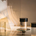 A Clérachic lamp with a black cap on a round glass tray, with a second fluted lamp partly visible at the right edge.