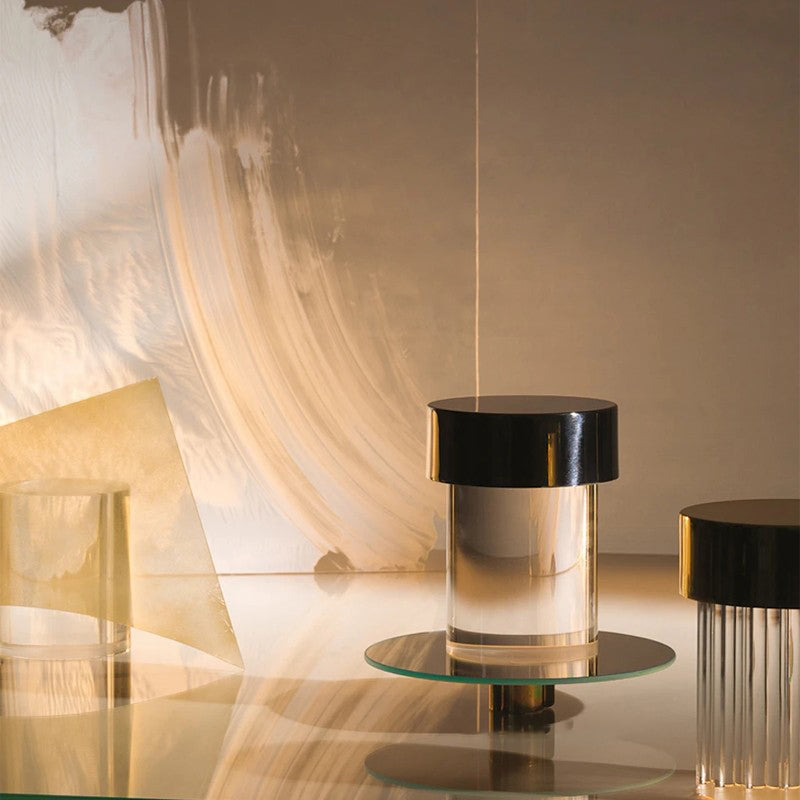 A Clérachic lamp with a black cap on a round glass tray, with a second fluted lamp partly visible at the right edge.