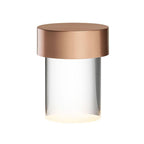 Large view of this Clérachic lamp on white, with a brushed rose gold cap over clear smooth glass and a warm glow at the base.