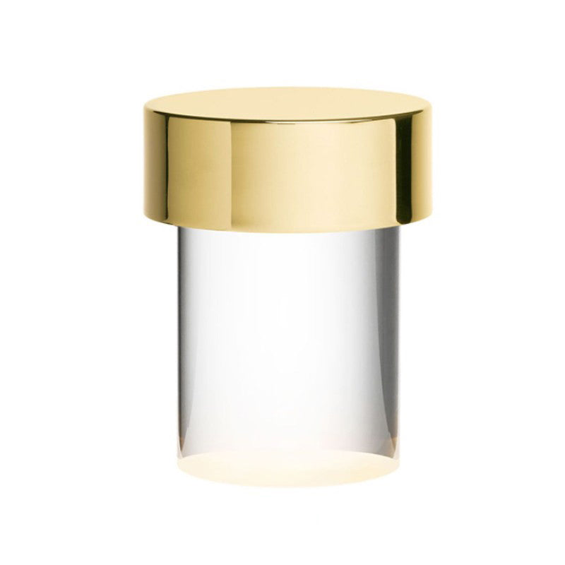 Large view of this Clérachic lamp on white, with a polished gold cap over a clear smooth glass body and a warm glow at the base.